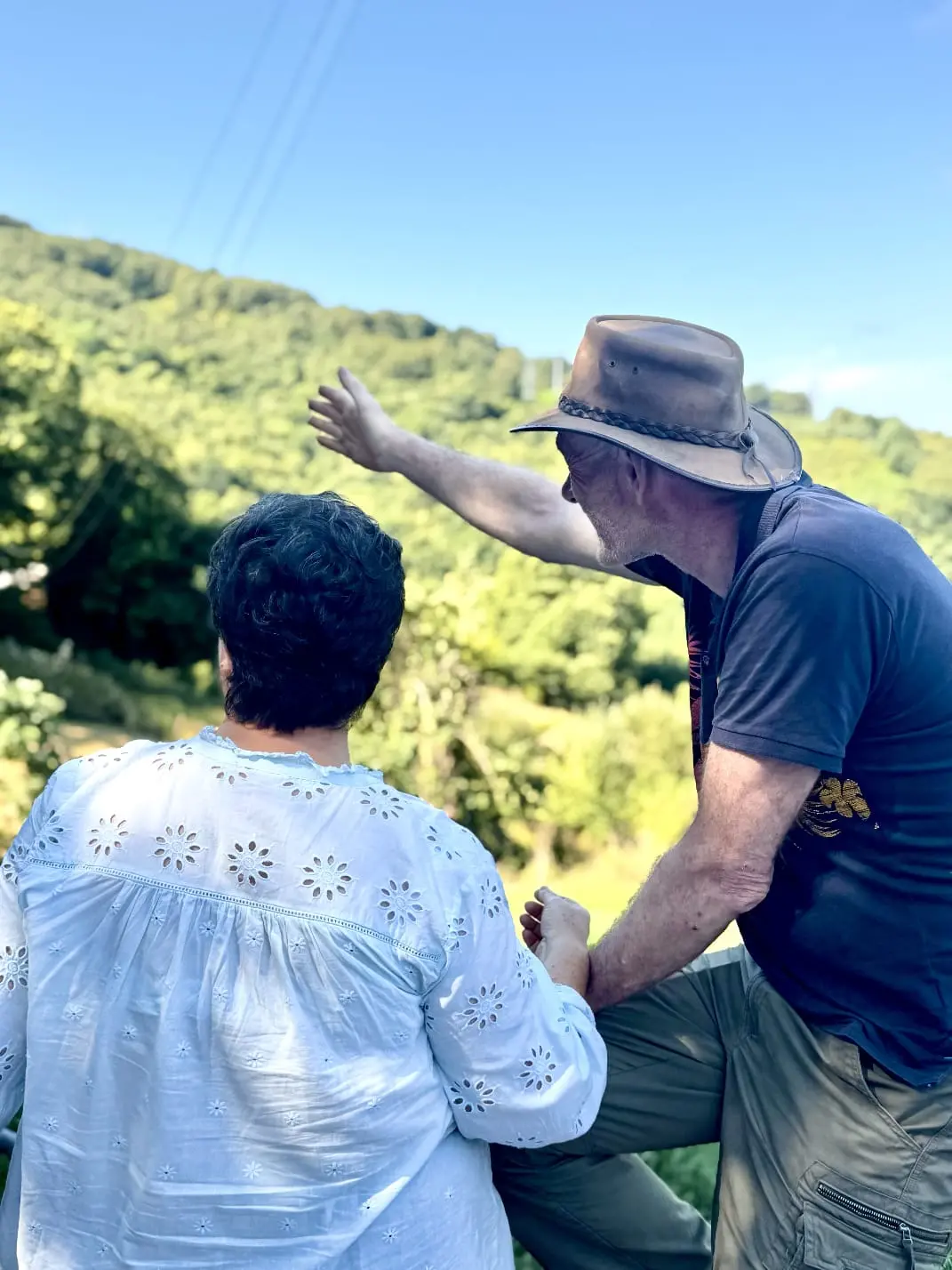 Dúas persoas observando e sinalando a paisaxe galega